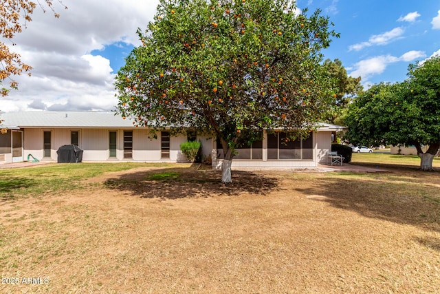 rear view of house with a lawn and a sunroom