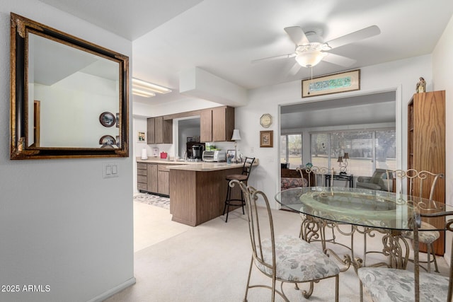 dining space with light colored carpet, ceiling fan, and a toaster