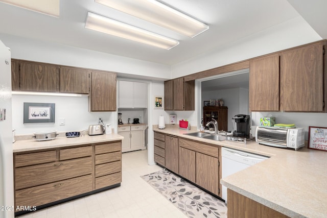 kitchen with light floors, a toaster, white dishwasher, a sink, and light countertops