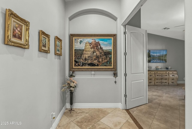 corridor featuring light tile patterned floors and lofted ceiling