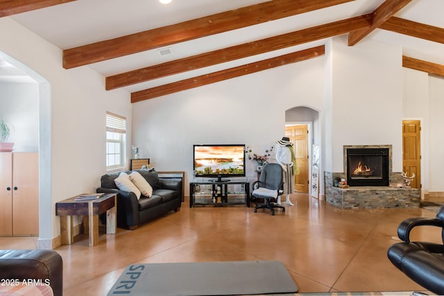 living area with a warm lit fireplace, visible vents, arched walkways, and beamed ceiling