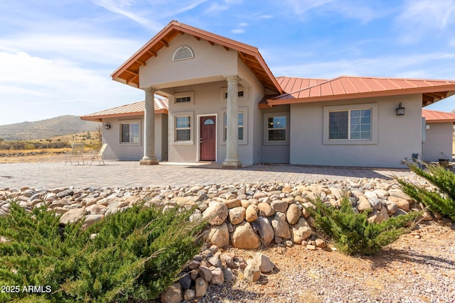 view of front facade featuring metal roof, a standing seam roof, a patio area, and stucco siding