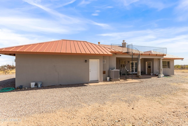 view of front of property with a standing seam roof, central AC unit, metal roof, and stucco siding