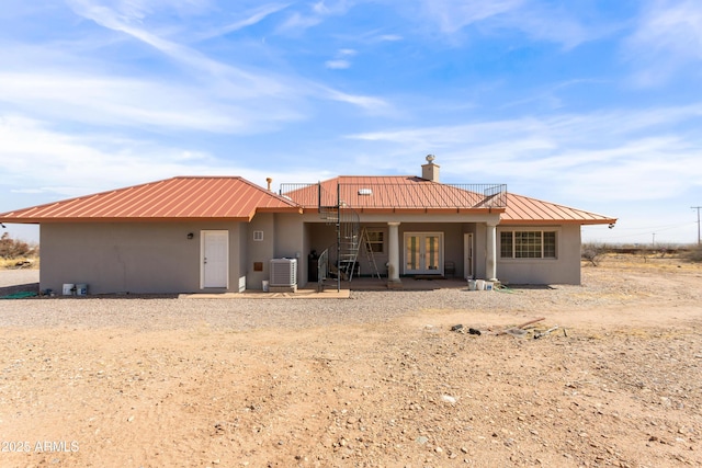 view of front of property featuring french doors, metal roof, a chimney, and stucco siding