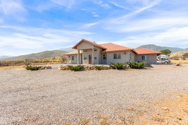 view of front facade with metal roof, a mountain view, and stucco siding