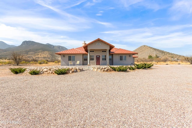 view of front facade featuring metal roof, a chimney, a mountain view, and stucco siding