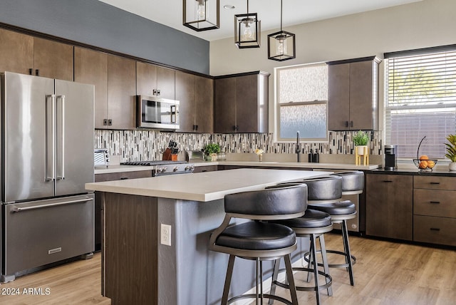 5725 S 101st St, Mesa, AZ 85212 - kitchen featuring light wood finished floors, a center island, decorative backsplash, appliances with stainless steel finishes, and a breakfast bar area