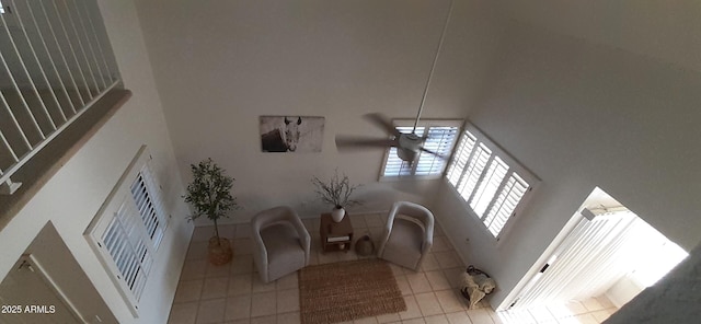 tiled living area featuring a towering ceiling and ceiling fan