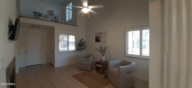 sitting room featuring a high ceiling, ceiling fan, and tile patterned flooring