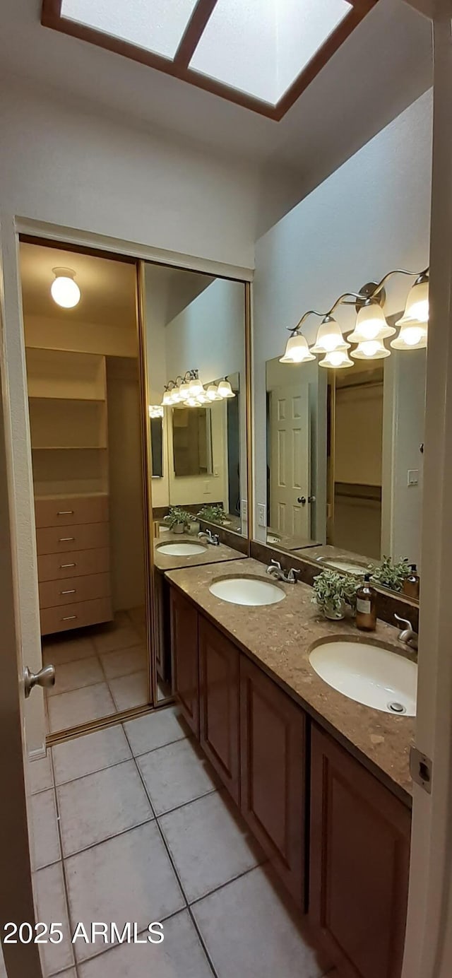 full bathroom featuring tile patterned flooring, double vanity, and a skylight