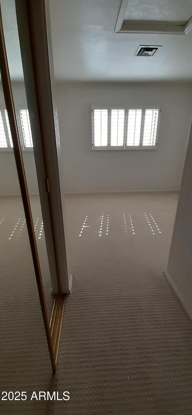 empty room featuring carpet and baseboards