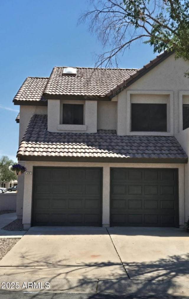 traditional-style house with an attached garage, stucco siding, a tiled roof, and concrete driveway