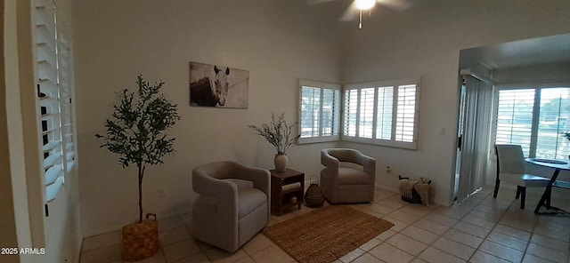 living area featuring light tile patterned floors, ceiling fan, and baseboards