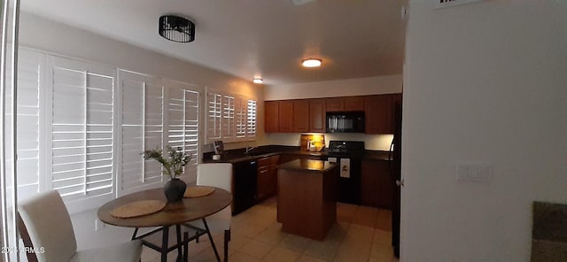 kitchen with black appliances, dark countertops, a center island, a sink, and brown cabinetry