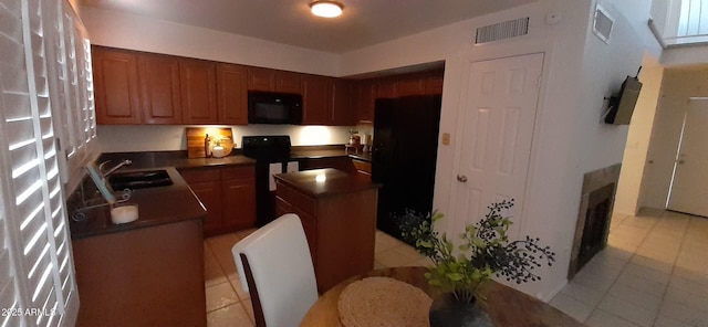 kitchen featuring black appliances, a center island, light tile patterned floors, and a sink