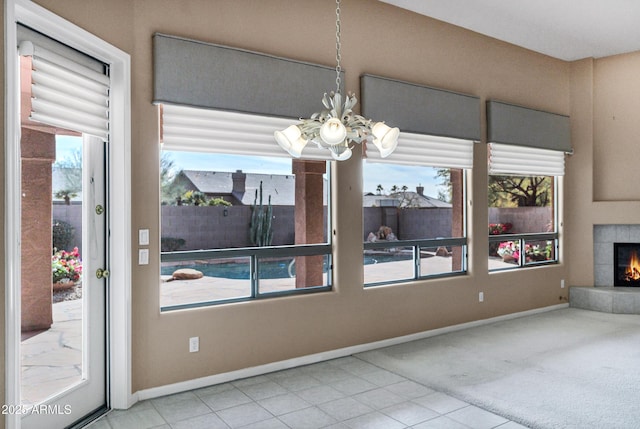 unfurnished dining area with a tiled fireplace, an inviting chandelier, and carpet floors