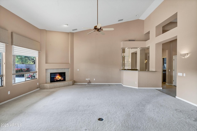 unfurnished living room featuring high vaulted ceiling, a tile fireplace, ceiling fan, and carpet flooring