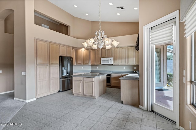 kitchen featuring light tile patterned floors, sink, a kitchen island, decorative light fixtures, and black fridge