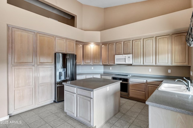 kitchen with sink, light tile patterned floors, a high ceiling, a center island, and black fridge