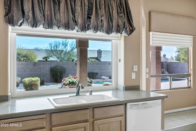 kitchen with white dishwasher, sink, light brown cabinetry, and light tile patterned floors