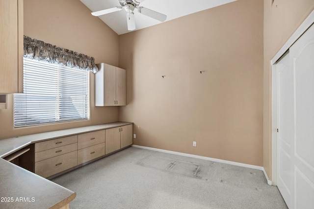 kitchen featuring ceiling fan, high vaulted ceiling, light colored carpet, and light brown cabinetry