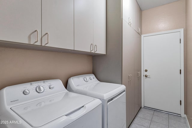 clothes washing area featuring washer and clothes dryer, light tile patterned floors, and cabinets