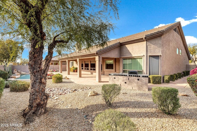 rear view of property with a fenced in pool and a patio