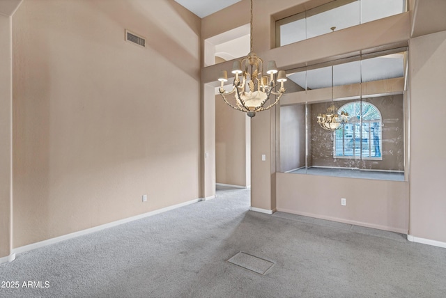 carpeted spare room featuring a high ceiling and a chandelier