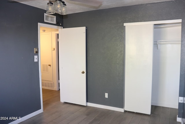 unfurnished bedroom with a closet, dark hardwood / wood-style flooring, and ceiling fan