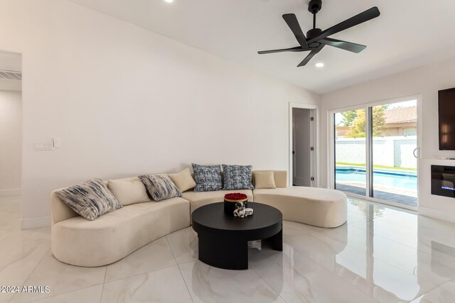 living room featuring ceiling fan, light tile patterned floors, and lofted ceiling