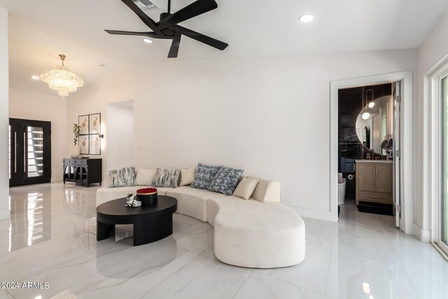 tiled living room featuring ceiling fan with notable chandelier and vaulted ceiling