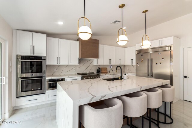 kitchen featuring pendant lighting, stainless steel appliances, backsplash, light tile patterned floors, and wall chimney range hood