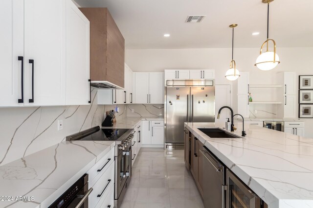 kitchen with white cabinets, high quality appliances, pendant lighting, backsplash, and sink