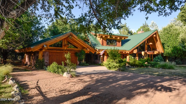 log home featuring a chimney, driveway, metal roof, and a garage