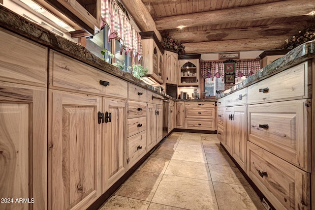 kitchen with light brown cabinets, dark stone counters, beam ceiling, wooden ceiling, and light tile patterned flooring