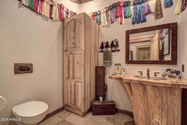 bathroom with tile patterned flooring, toilet, baseboards, and a sink