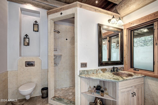 bathroom with tiled shower, toilet, tile walls, and vanity