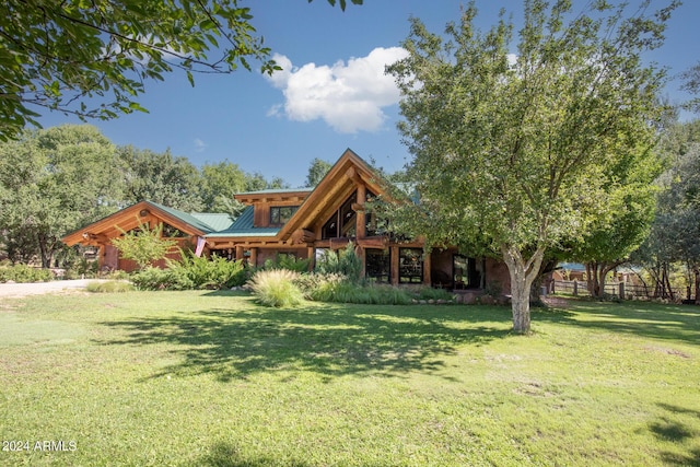 view of front of home featuring metal roof, log exterior, and a front lawn