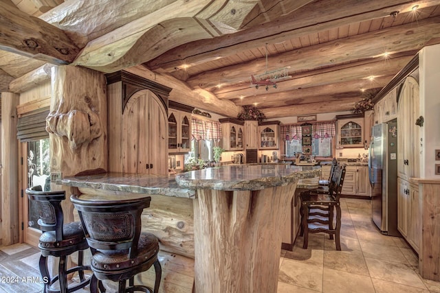 kitchen featuring beamed ceiling, a kitchen breakfast bar, glass insert cabinets, and freestanding refrigerator