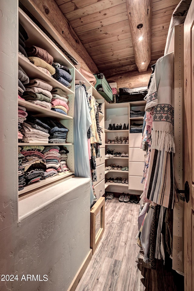 walk in closet with beamed ceiling and wood finished floors