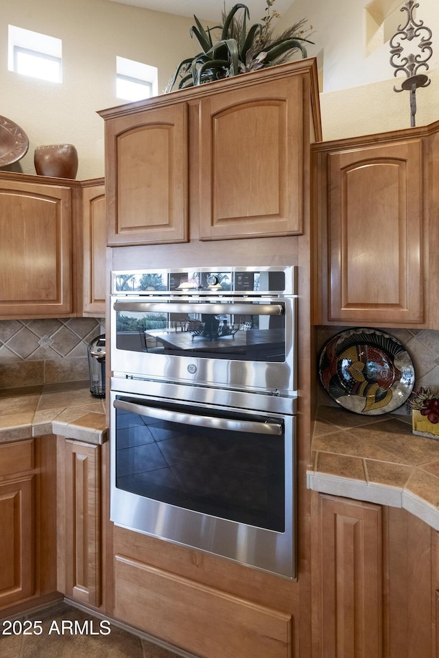 kitchen with tasteful backsplash, tile counters, and double oven