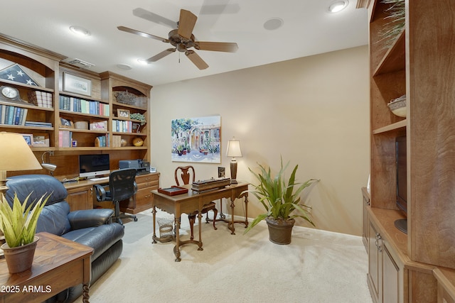 carpeted office space featuring built in desk and ceiling fan