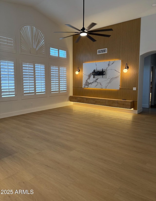 802 N Lisbon Dr, Chandler, AZ 85226 - unfurnished living room featuring arched walkways, lofted ceiling, a ceiling fan, wood finished floors, and baseboards