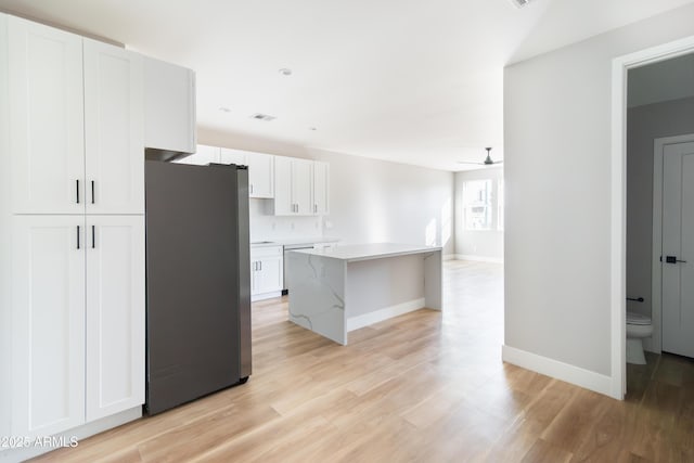 kitchen featuring white cabinetry, a center island, light wood-type flooring, ceiling fan, and stainless steel appliances