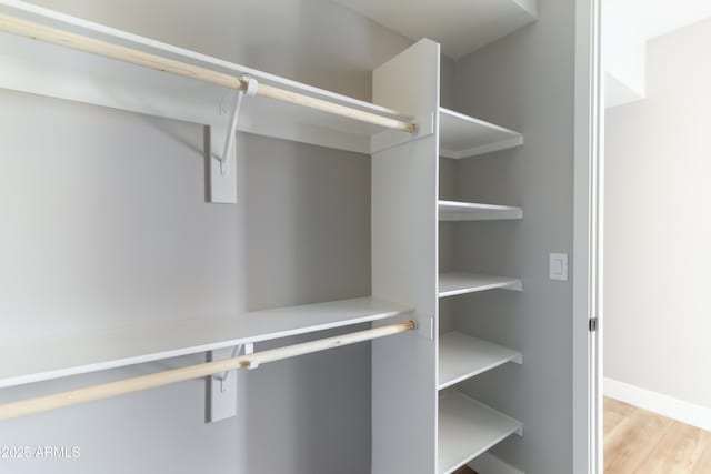 walk in closet with light hardwood / wood-style floors