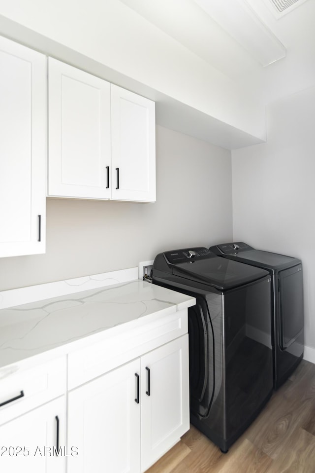 clothes washing area featuring dark wood-type flooring, cabinets, and separate washer and dryer