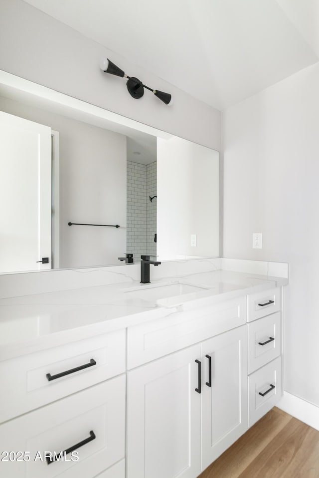 bathroom with vanity, tiled shower, and hardwood / wood-style floors