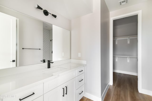 bathroom featuring hardwood / wood-style flooring, vanity, and a tile shower