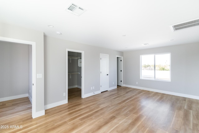 unfurnished bedroom featuring a spacious closet and light wood-type flooring