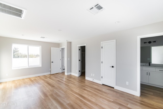 unfurnished bedroom featuring sink, connected bathroom, and light hardwood / wood-style floors